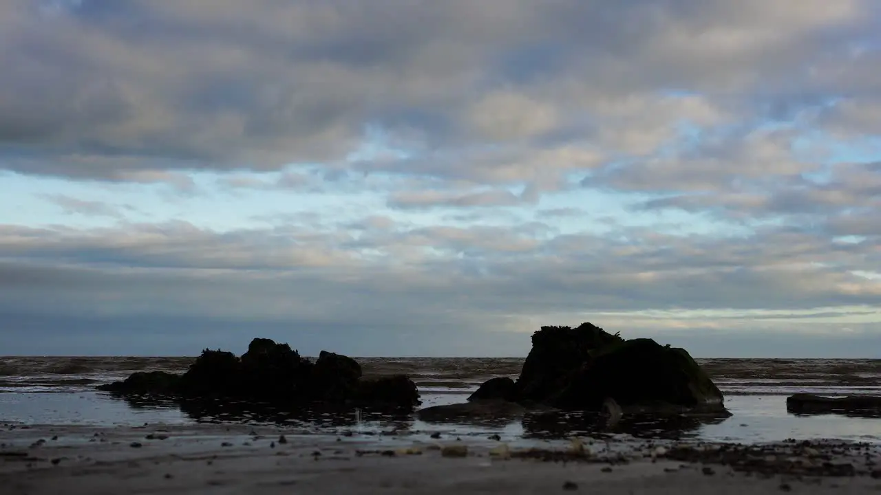 Low angle view from the sandy beach on the rock and waves cloudy sky in Dundalk Ireland