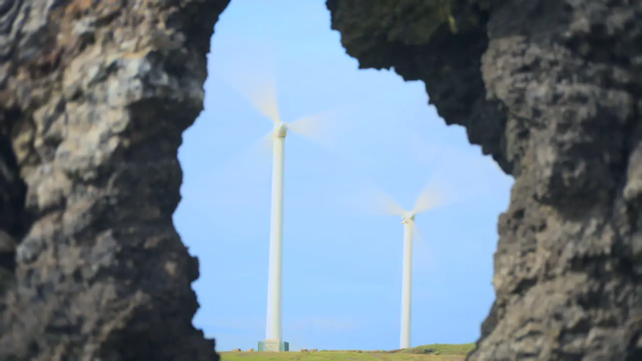 Windmills spinning in sunshine framed by rock formation