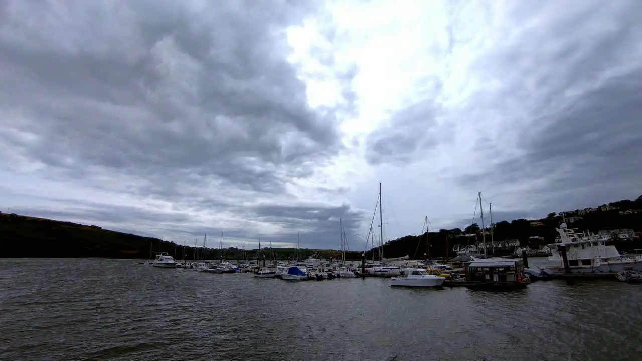 Time-lapse of stormy clouds rushing over marina with boats