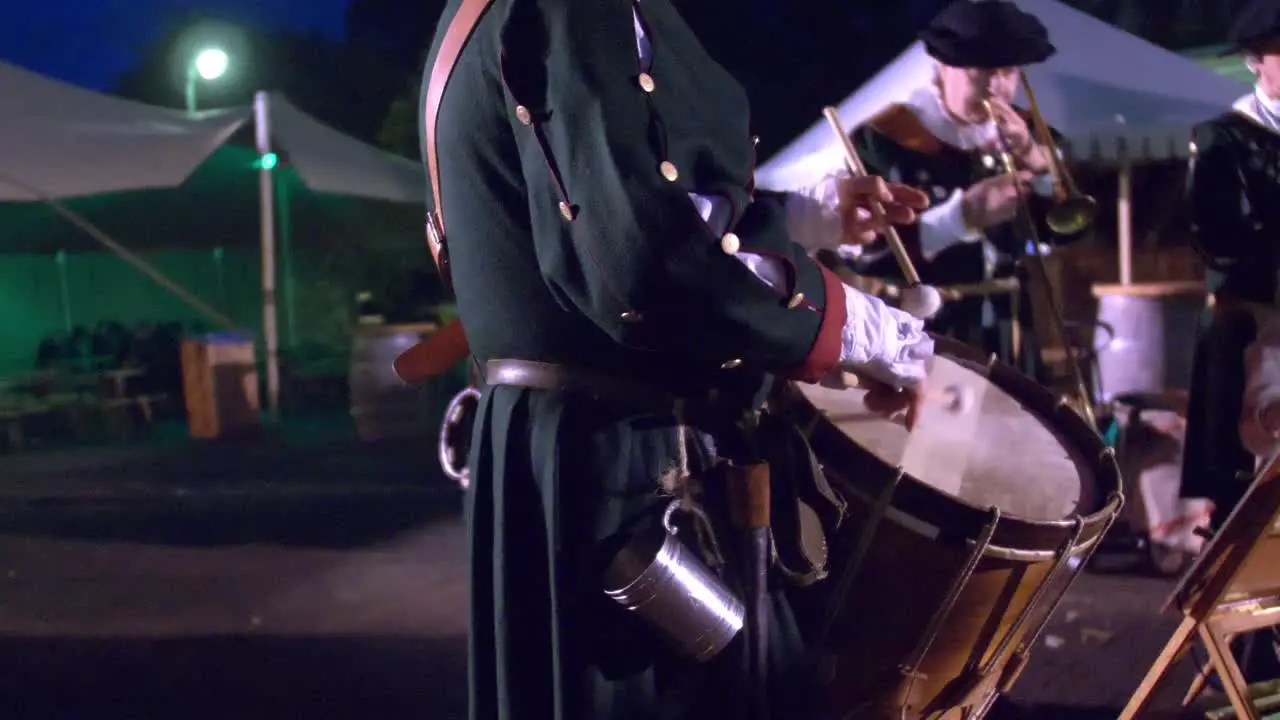 man in historic uniform playing drums in military orchestra at night time