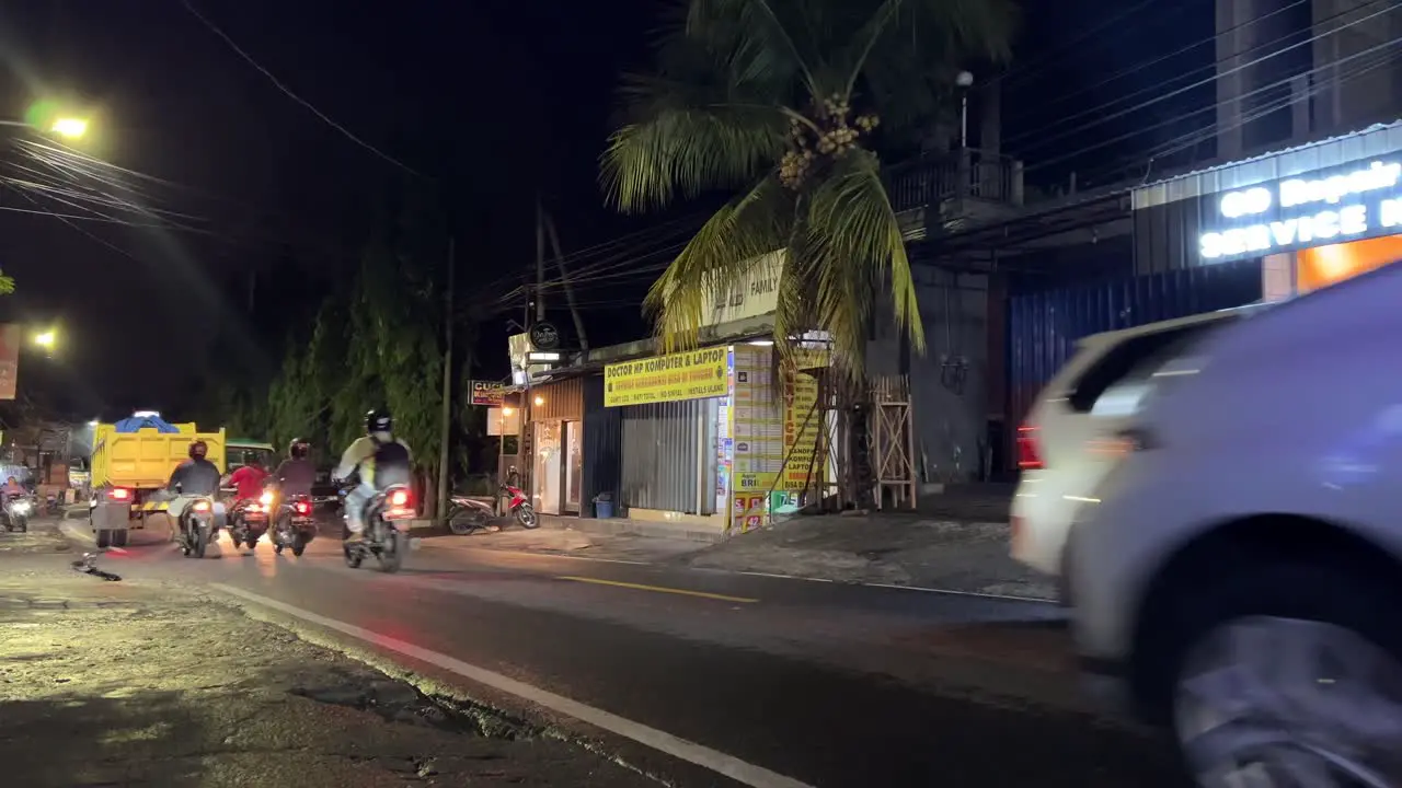 Road Traffic in Bali Street with local shops on the roadside during nighttime Static shot