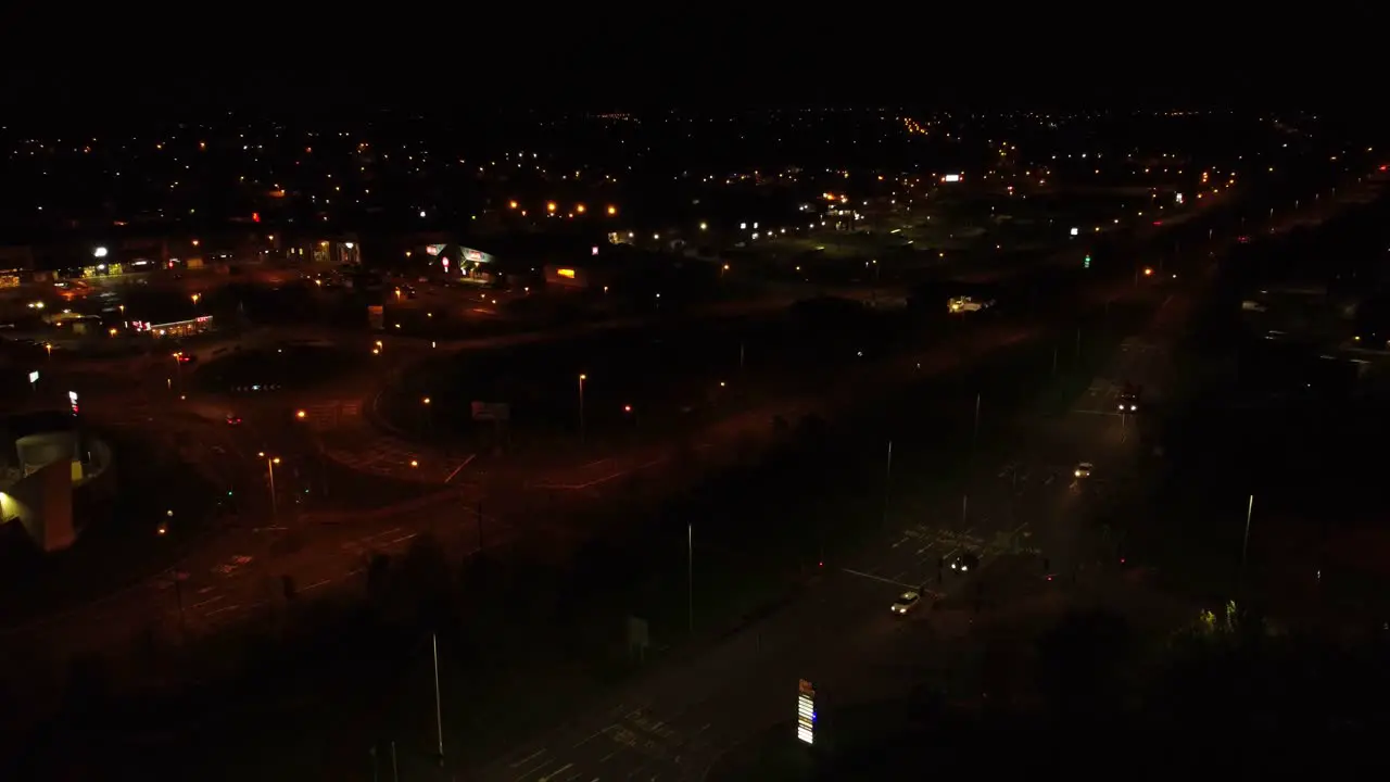 Nighttime traffic headlights driving British rural town highway intersection aerial view