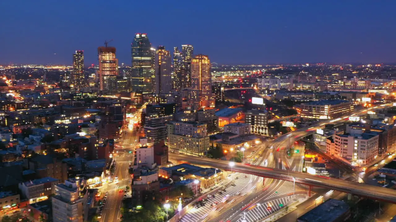 an aerial cinematic dusk to night time lapse by a busy highway in Brooklyn New York with cars trains planes in motion