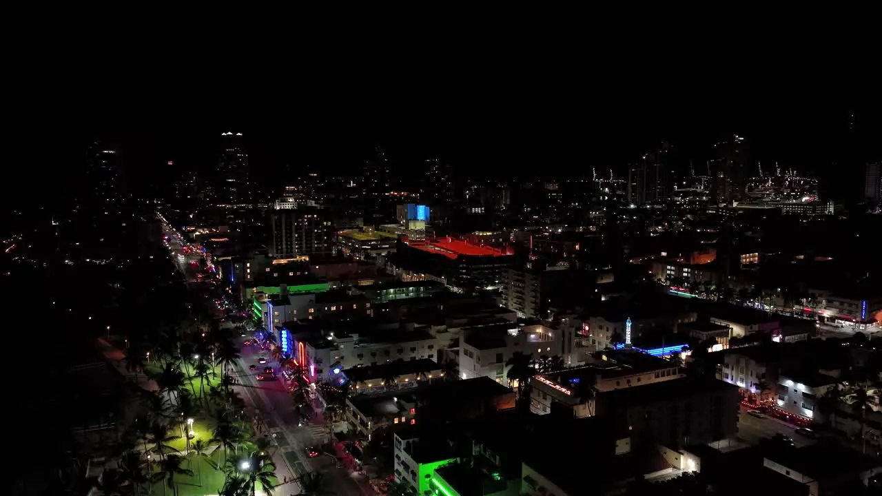 Nightly aerial drone footage of Miami USA rising pedestal shot showing many different colored lights over the buildings