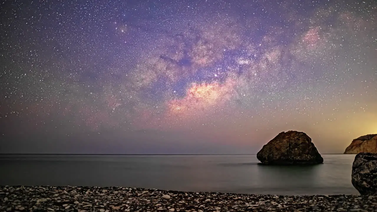 Timelapse of the milky way and the stars on a coast with rocks at night