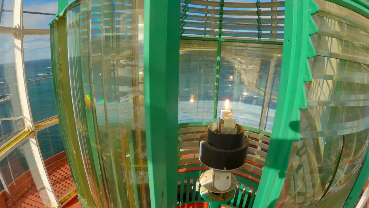 Static inside shot of the lantern room of a lighthouse during a bright sunny day with the fresnel lens moving by the lamp light