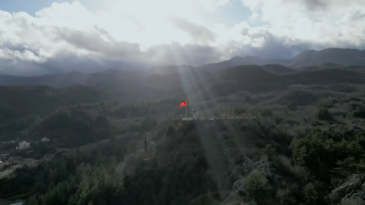 Fluttering Flag of Montenegro With Sky Rays Penetrating Dark Clouds Dramatic Aerial Panorama