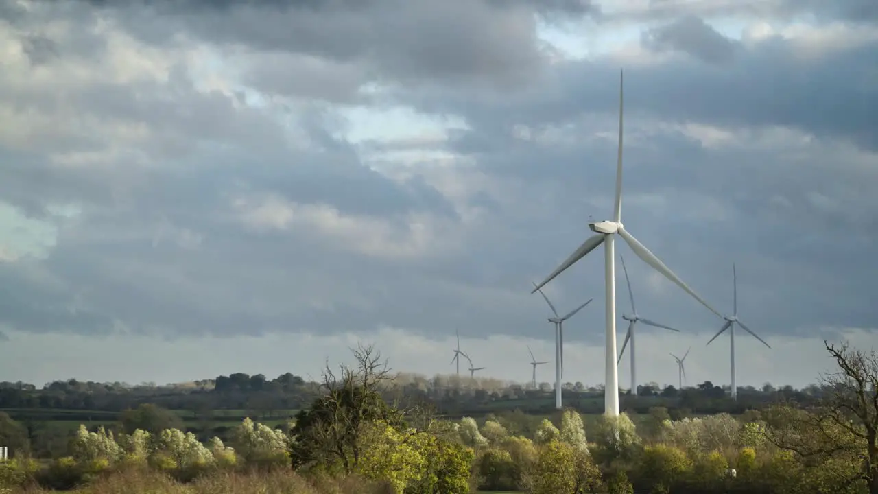 Windmills in a forested landscape wind farm on a cloudy day 4k