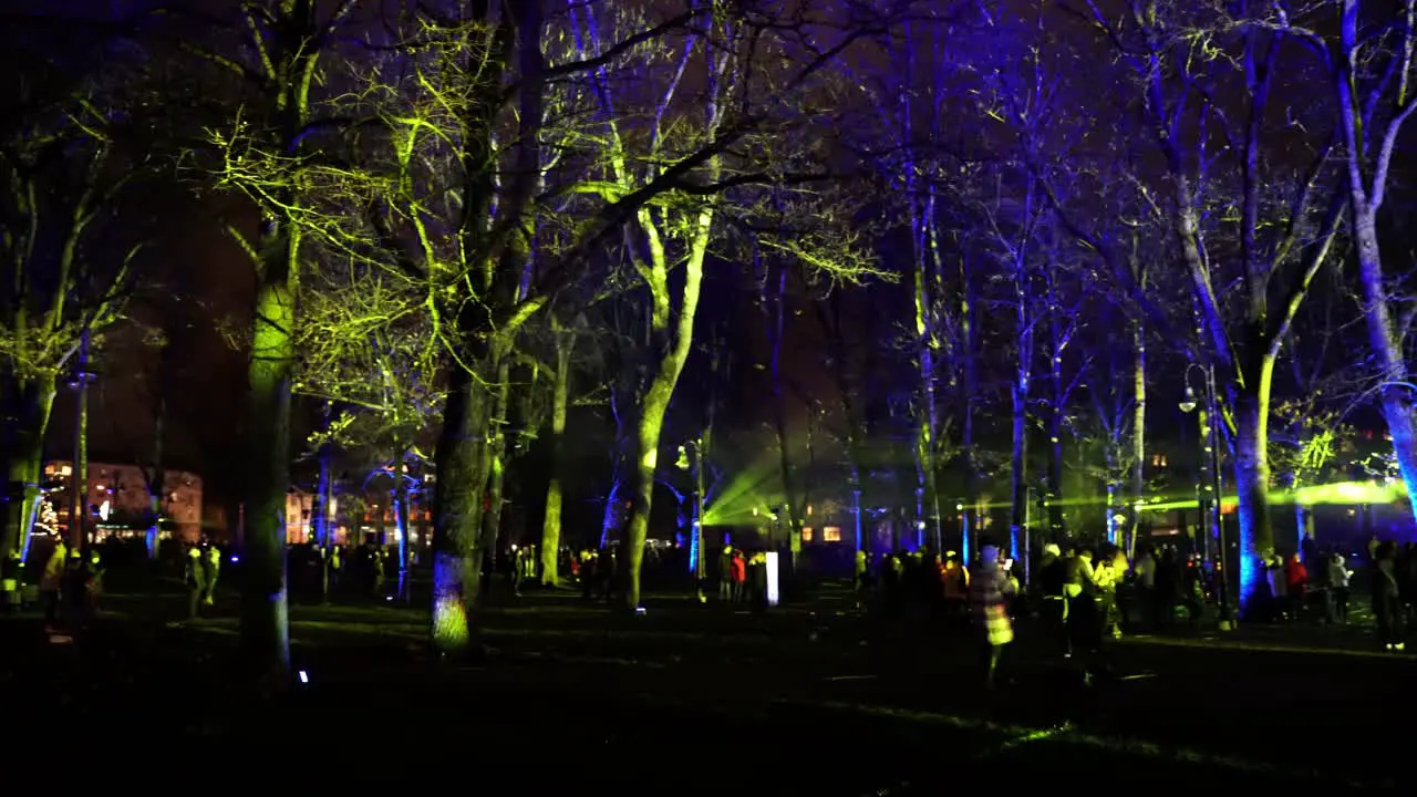 Pan right shot of people in square admiring laser show at night