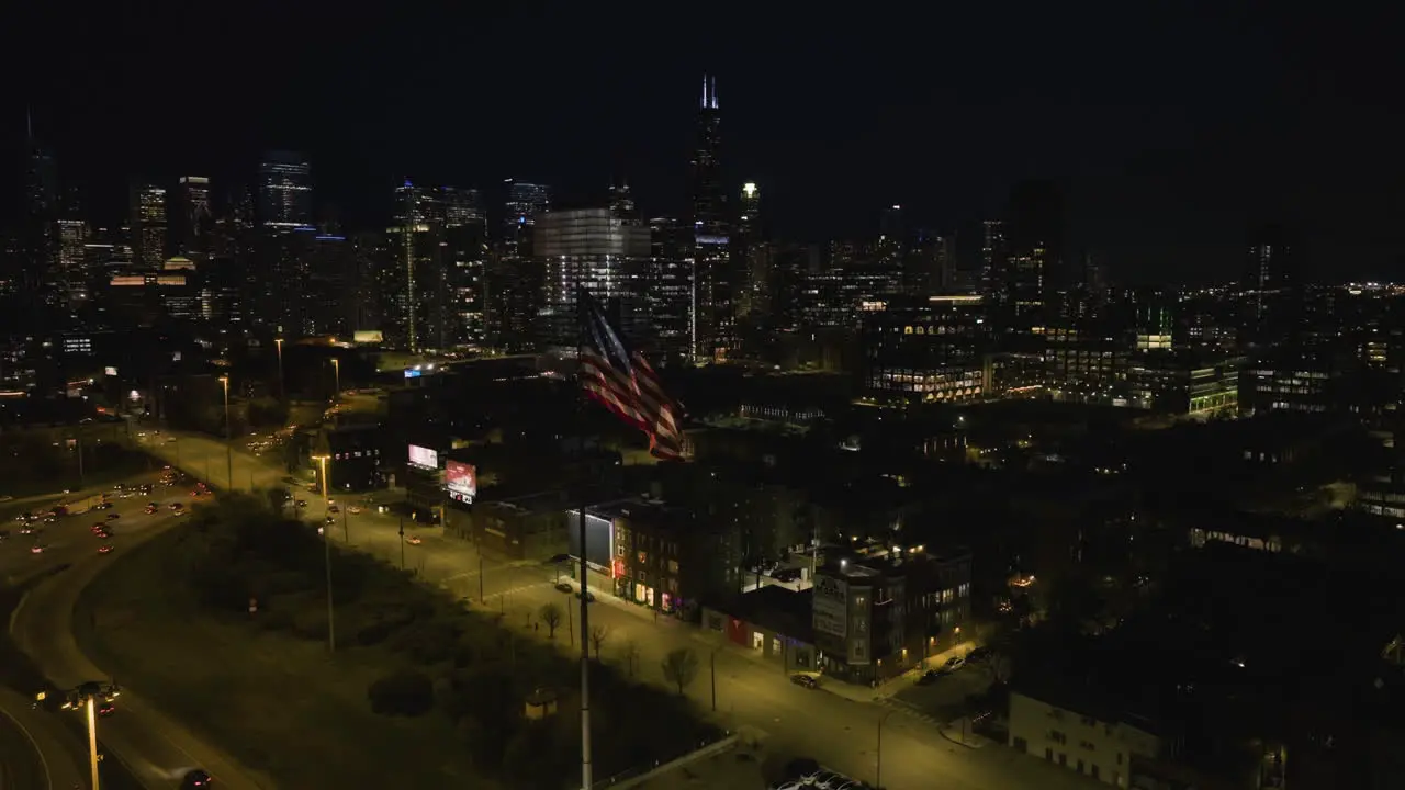 Aerial view still in front of a waving US Flag in Chicago city nighttime in Illinois USA