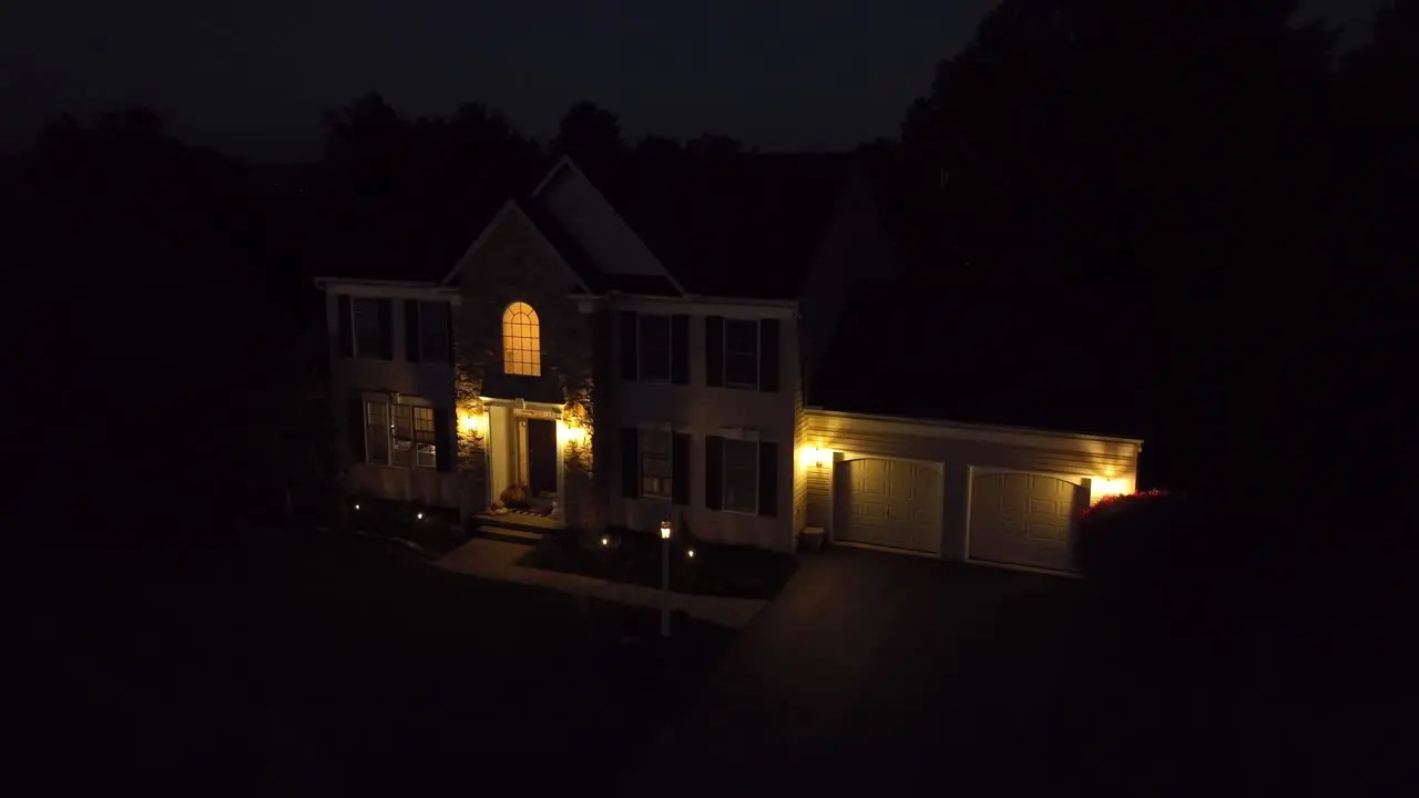 American Colonial two story home at night with garage and front porch lights on