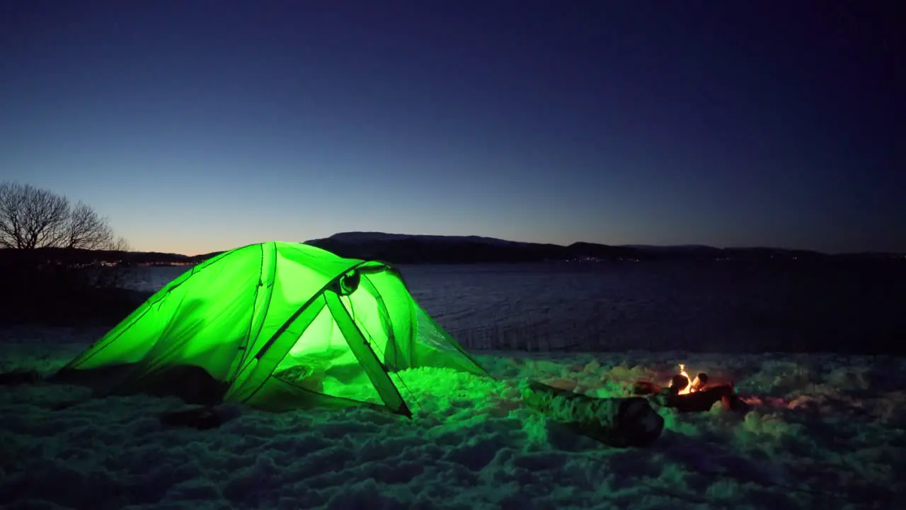 Illuminated Green Camping Tent With Camp Fire At Night