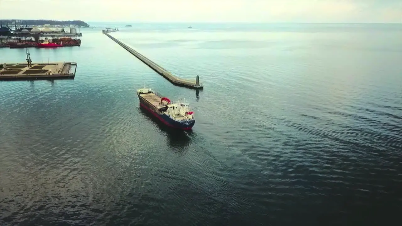 Drone flying and following big cargo ship going into the port