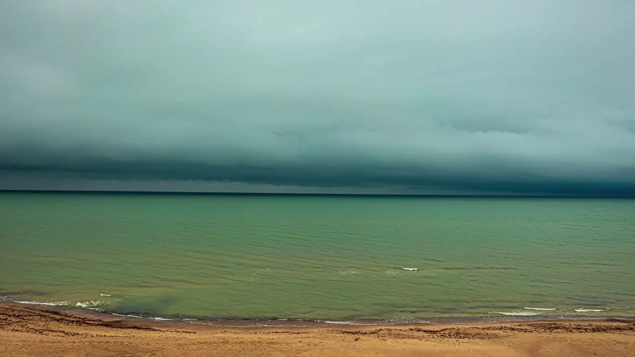 High angle shot of dark rain clouds passing by along seaside with sea waves crashing in timelapse on a cloudy day