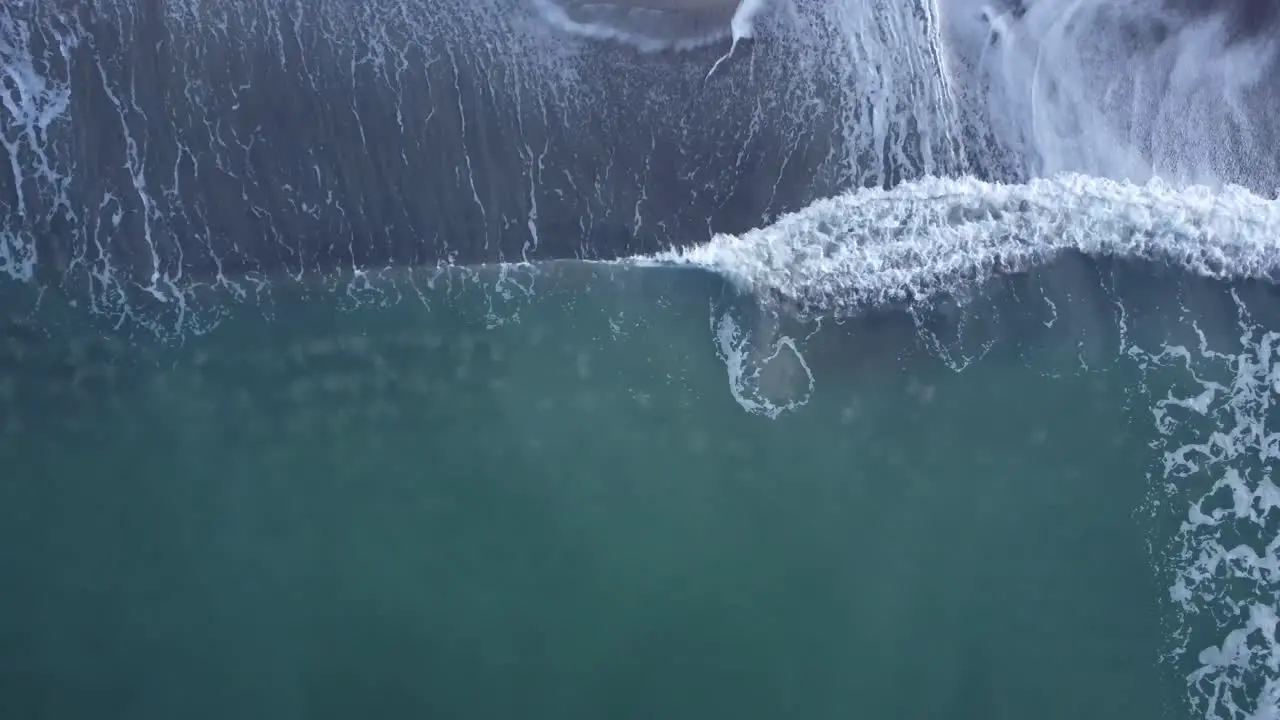 Top down drone footage of waves crashing on a beach