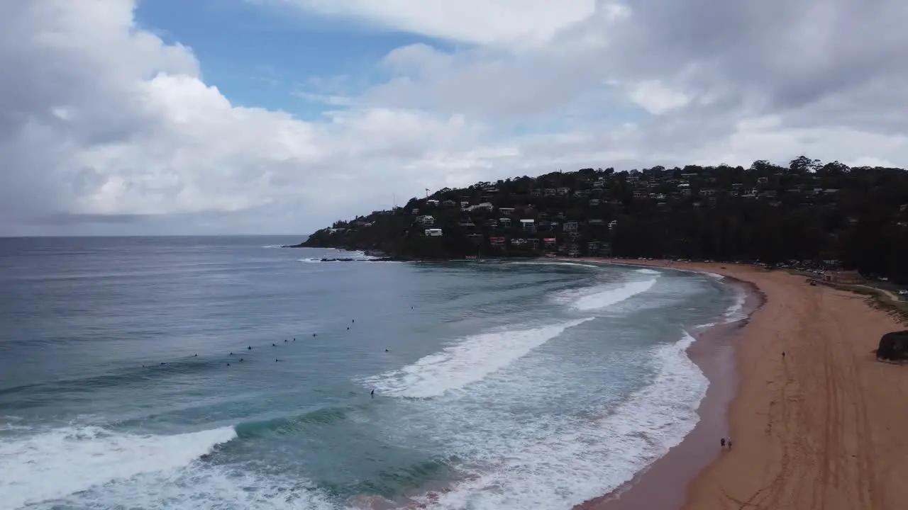 Drone flying towards surfers on a beautiful surf beach on a cloudy day