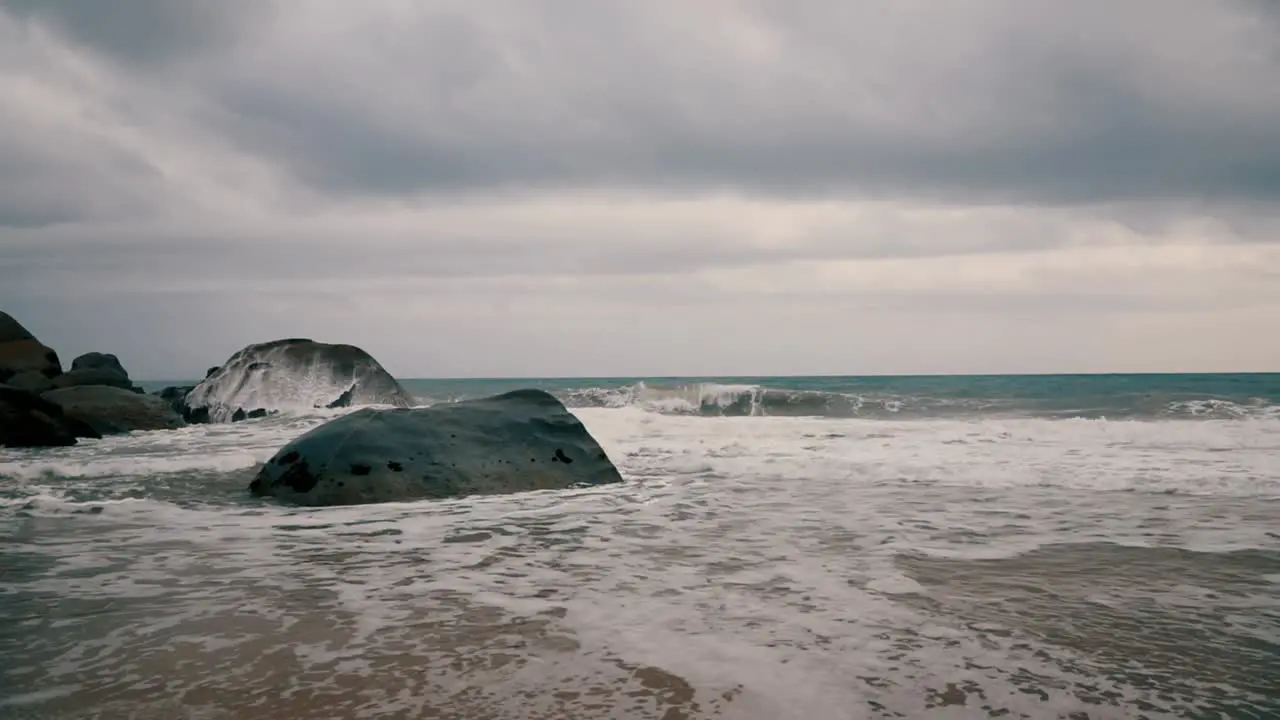 Slow motion water splashing on the rocks in a seashore on a cloudy day with blue sea