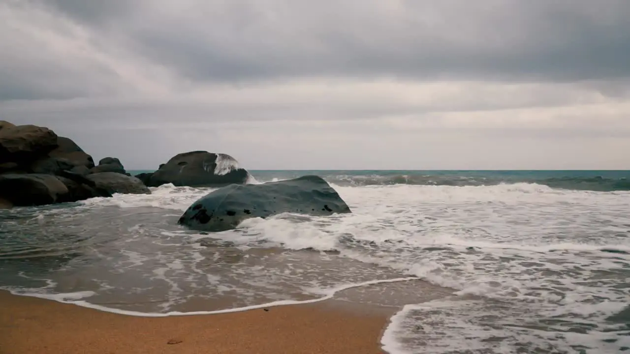 Water splashing on the rocks in a seashore on a cloudy day with blue sea