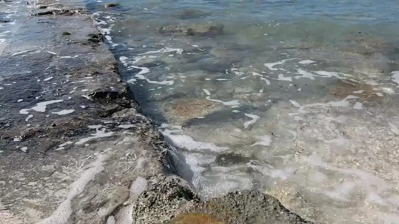 Calming waves wash against an old rock wall in the Bahamas