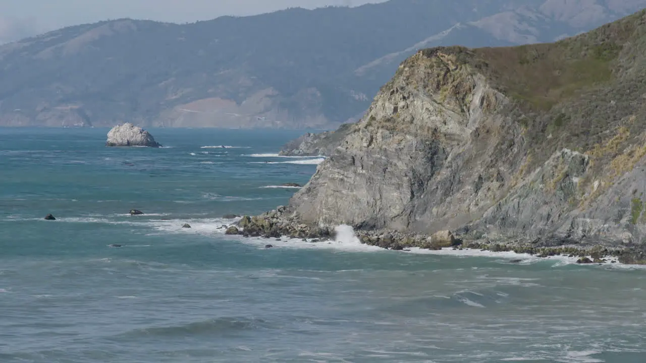 ocean view of cliff lined shore with crashing waves along the California coast of Big Sur California