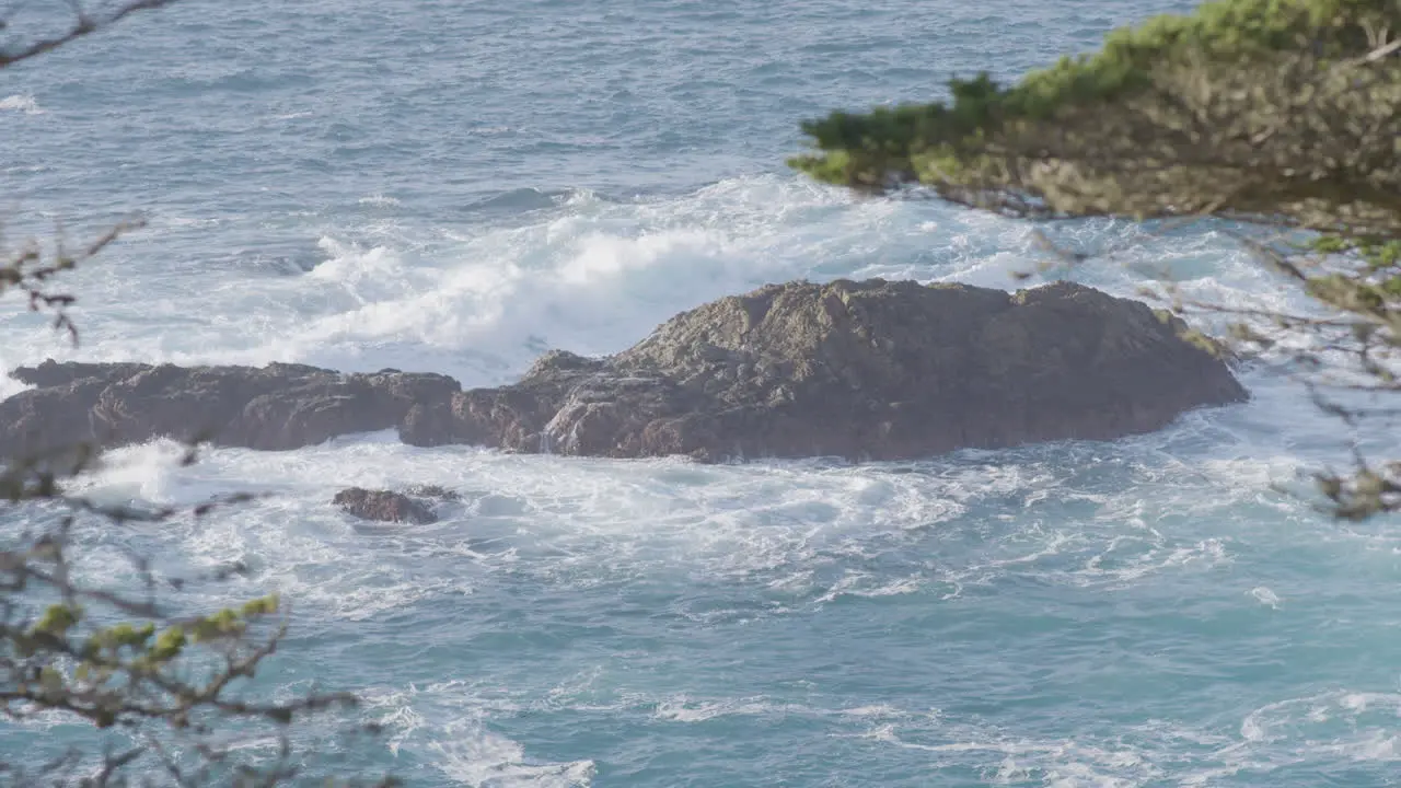 Panning shot of waves crashing along the boulders of Big Sur California Pacific Ocean