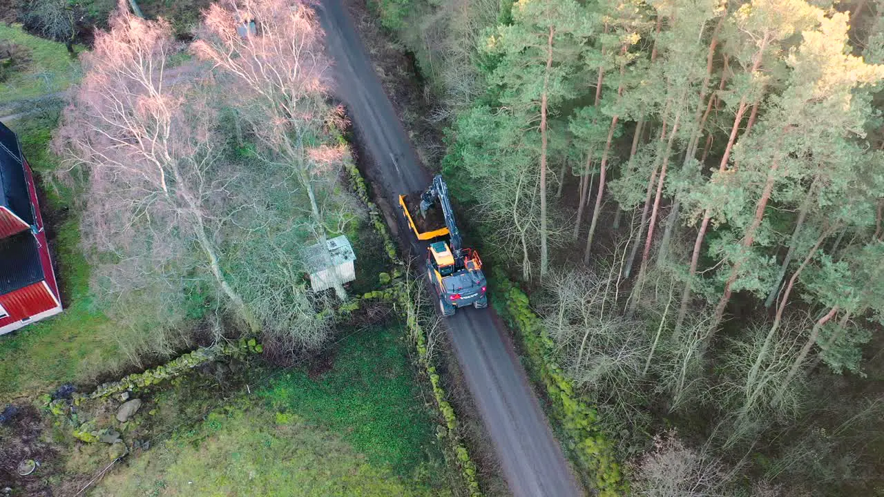 Aerial view of heavy machine digging a ditch by forest road