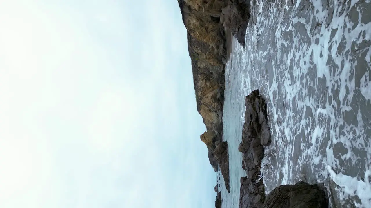 Vertical shot of waves crashing on shore along pacific coastline San Mateo County California Highway 1