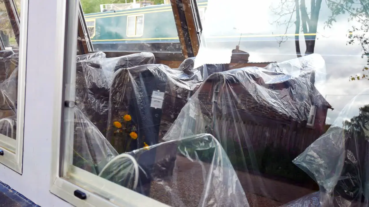 Plastic bag covered seating on tourist barge boat waiting empty on British canal during Covid pandemic