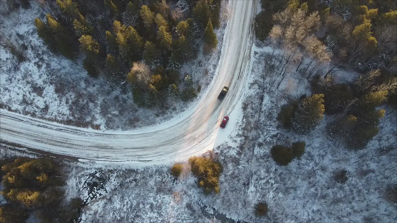 Top Down Shot Of A Pickup Truck Driving Past A Parked Car On Forest Road During Winter