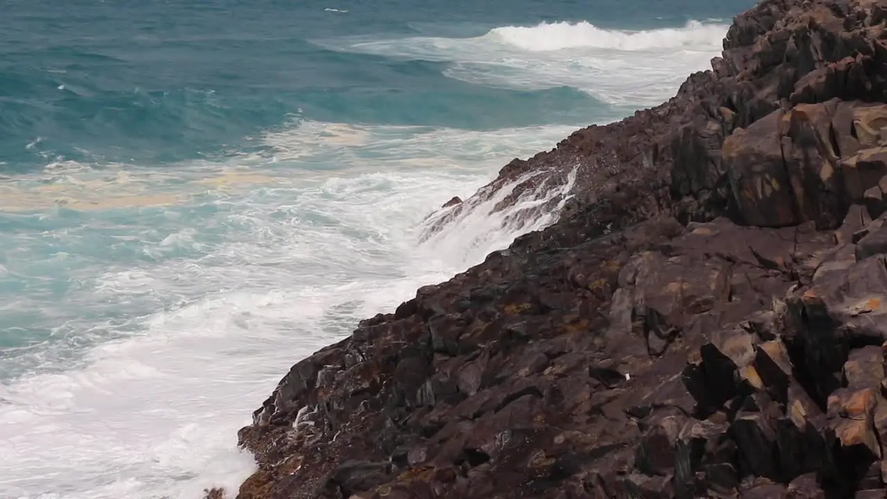 Tropical ocean waves slowly crashing onto rocks on the Noosa Heads National park hike in Noosa Heads Australia