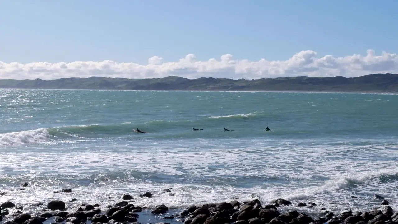 Surfing in Raglan surfers paddling and waiting for a wave to surf Waikato New Zealand Aotearoa