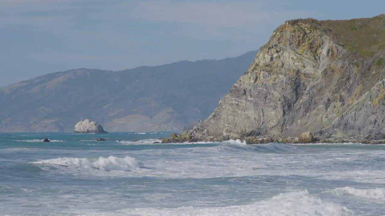 Stationary shot of waves rolling into the side of high cliff located in Big Sur California