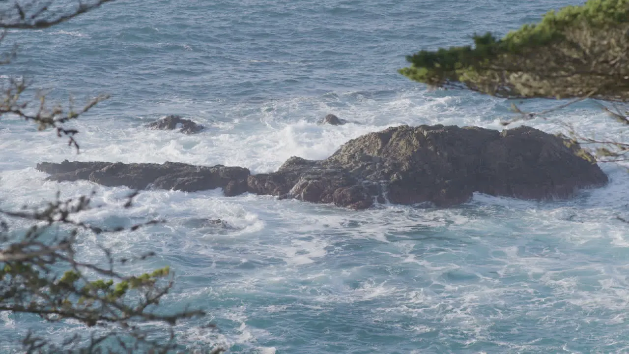 Stationary shot from above of waves crashing along a rock island on a Big Sur California beach