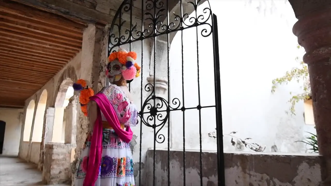 Catrina woman for the day of the dead walking in old house with flowers on her head