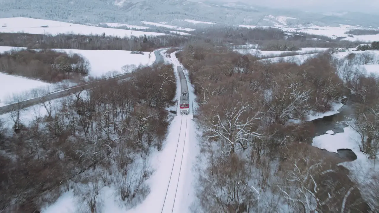 Intercity passenger train moving in winter landscape aerial view