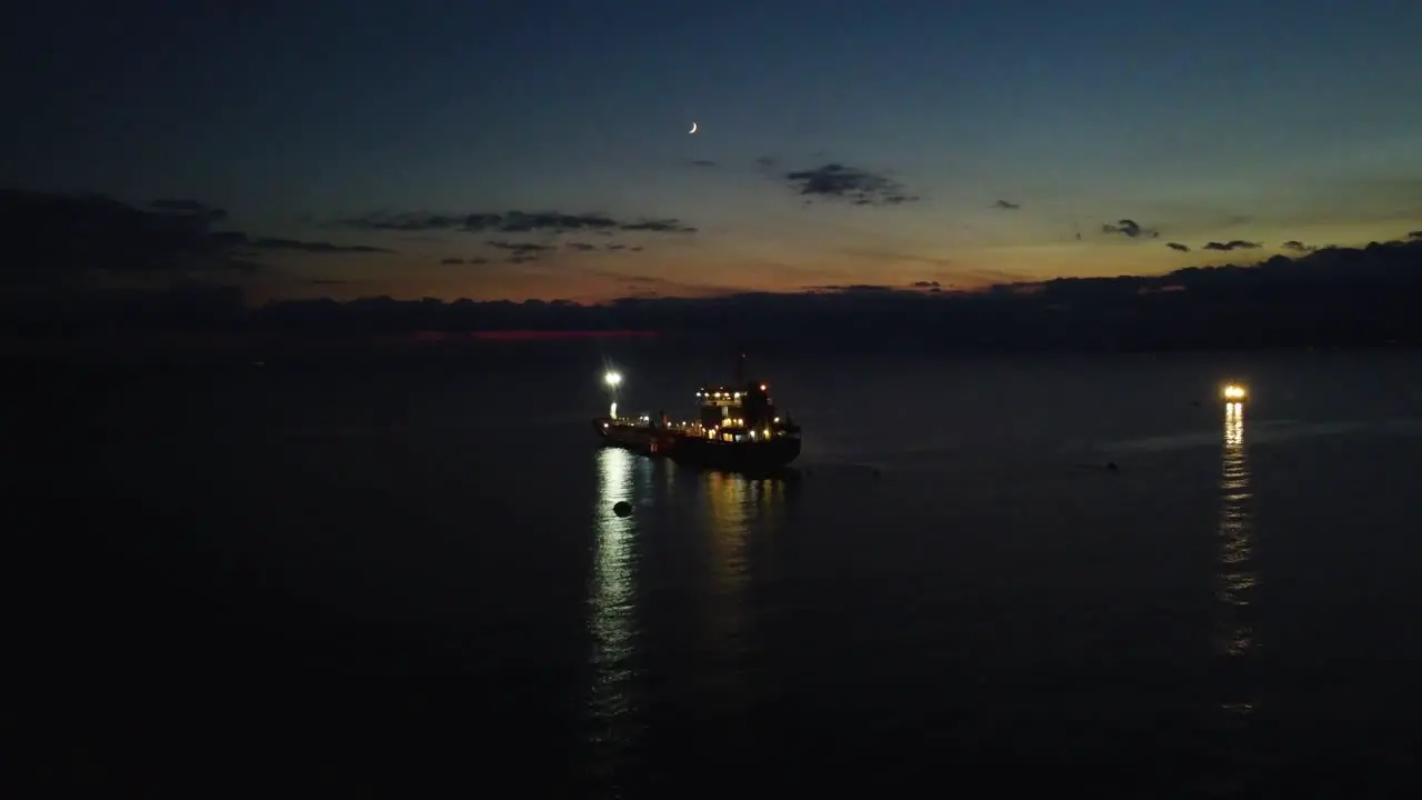 Aerial approaching boat oil tanker in sea at dusk night view