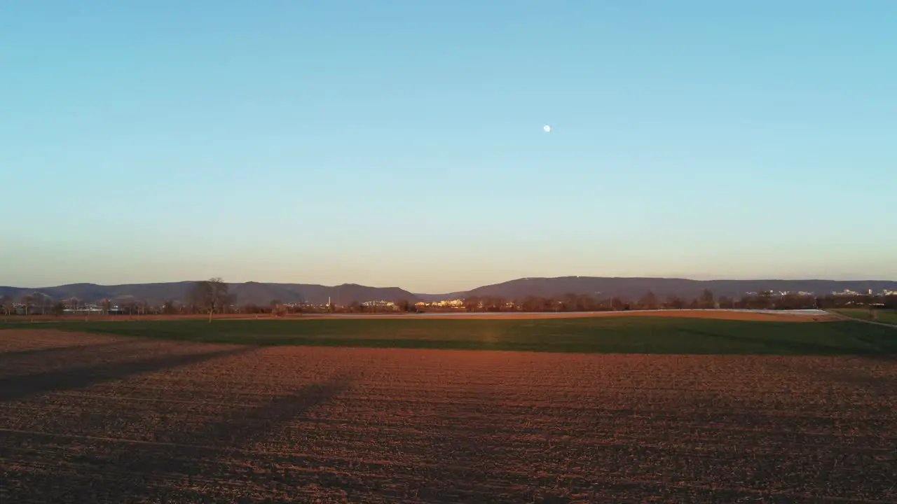 Zooming out of landscape over agricultural field during sunset with full moon on sky in Germany Europe