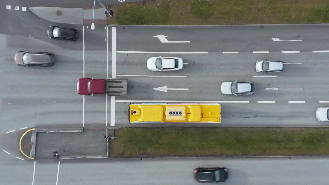 Cars moving along crossing intersection during green traffic light yellow public transport bus top down