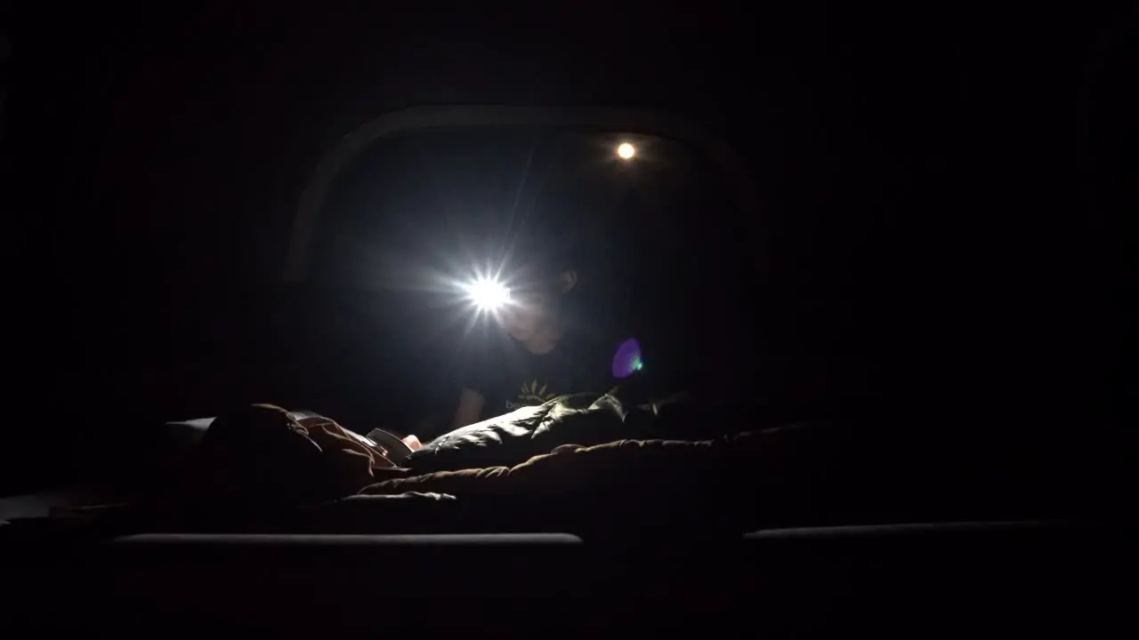 Boy reading in the dark wearing a headlamp to light up the darkness