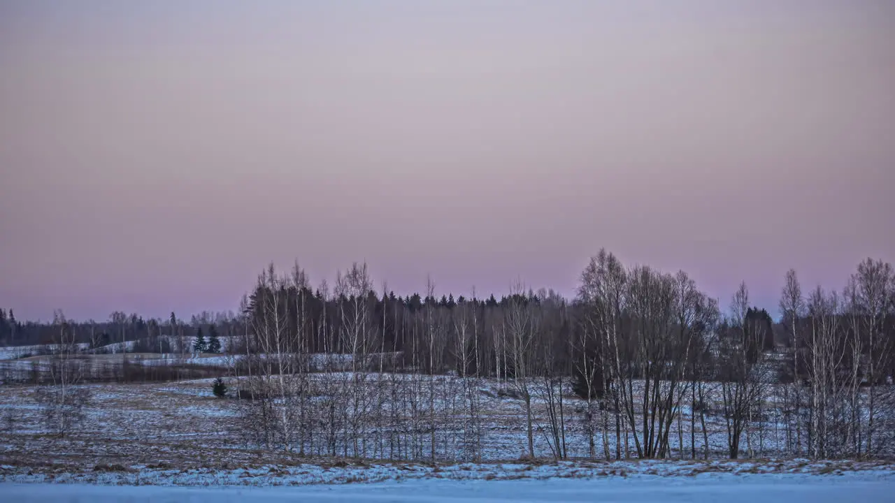 Static shot of moon sets just as the sun rising in the background at dawn in timelapse over rural landscape