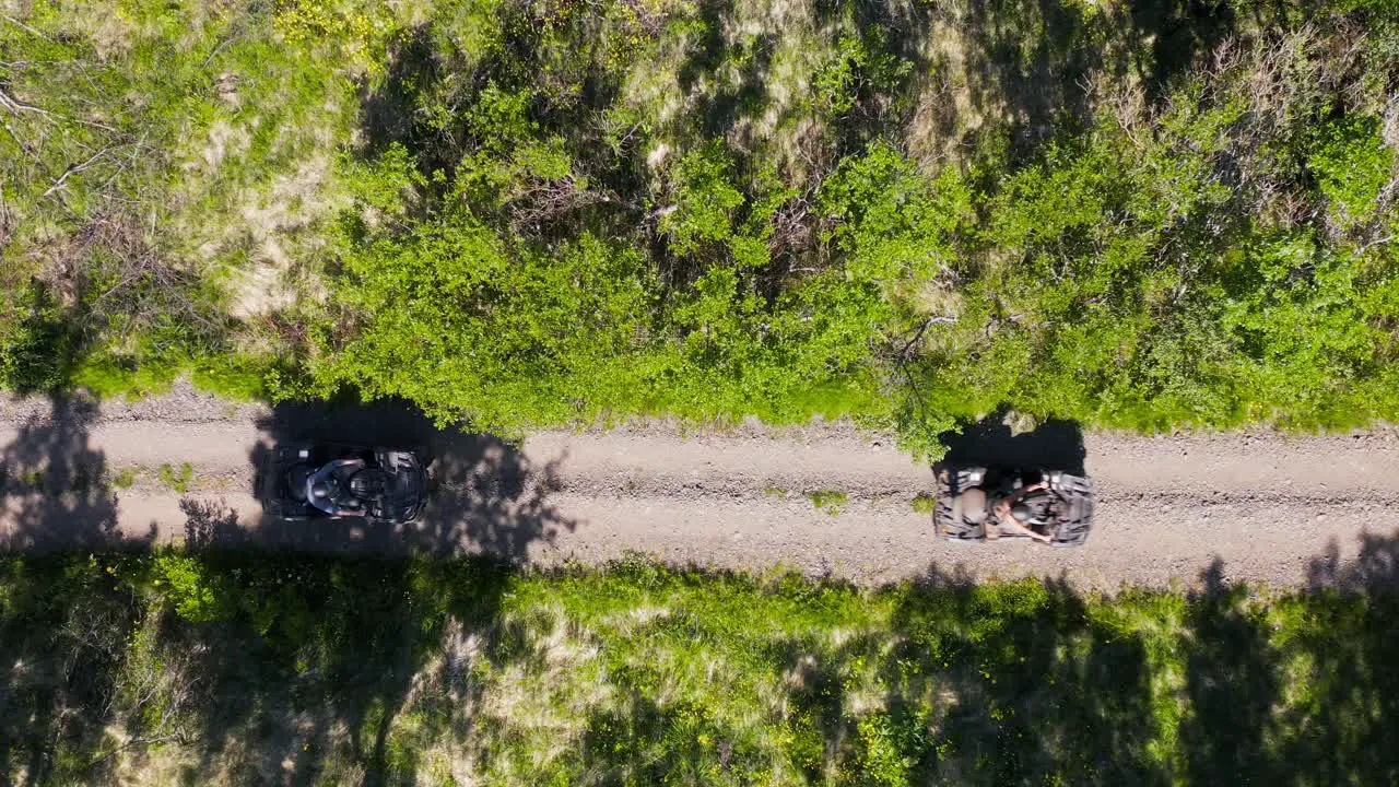 People on 4x4 quadbikes taking off on dirt trail in outdoors top down