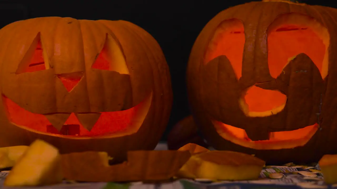 Happy Halloween 2 Jack O' Lanterns glowing in the dark wishing Happy Halloween carved Pumpkin decorations with burning candles inside