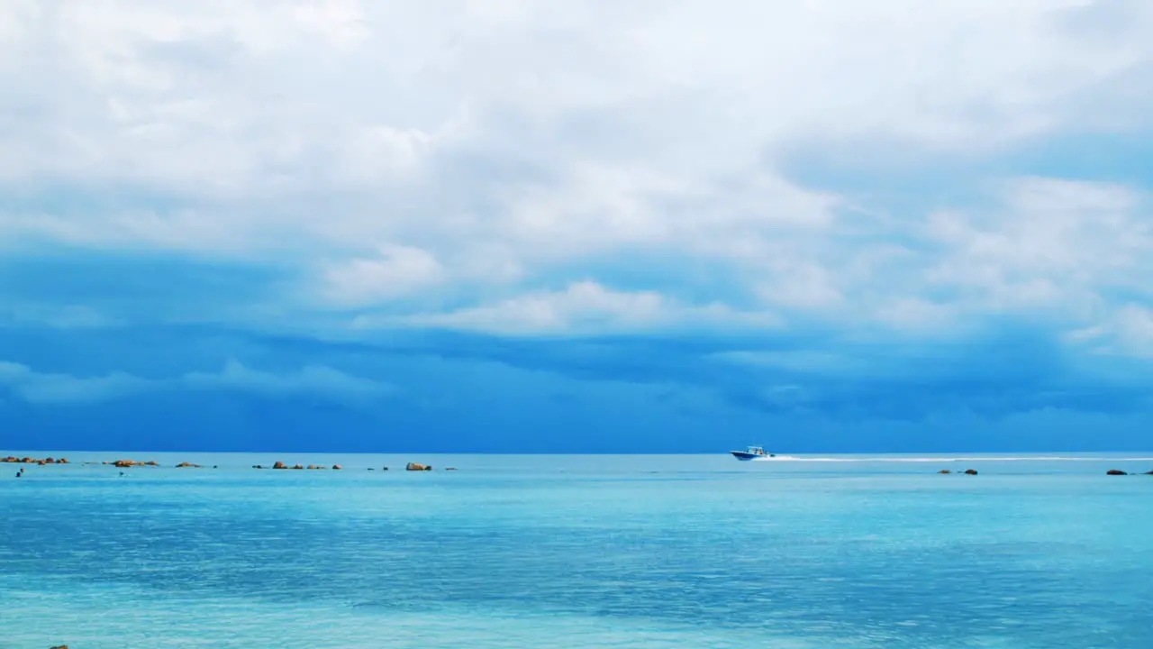 Boat sailing across vibrant blue Caribbean Sea before storm Slow Motion Pan