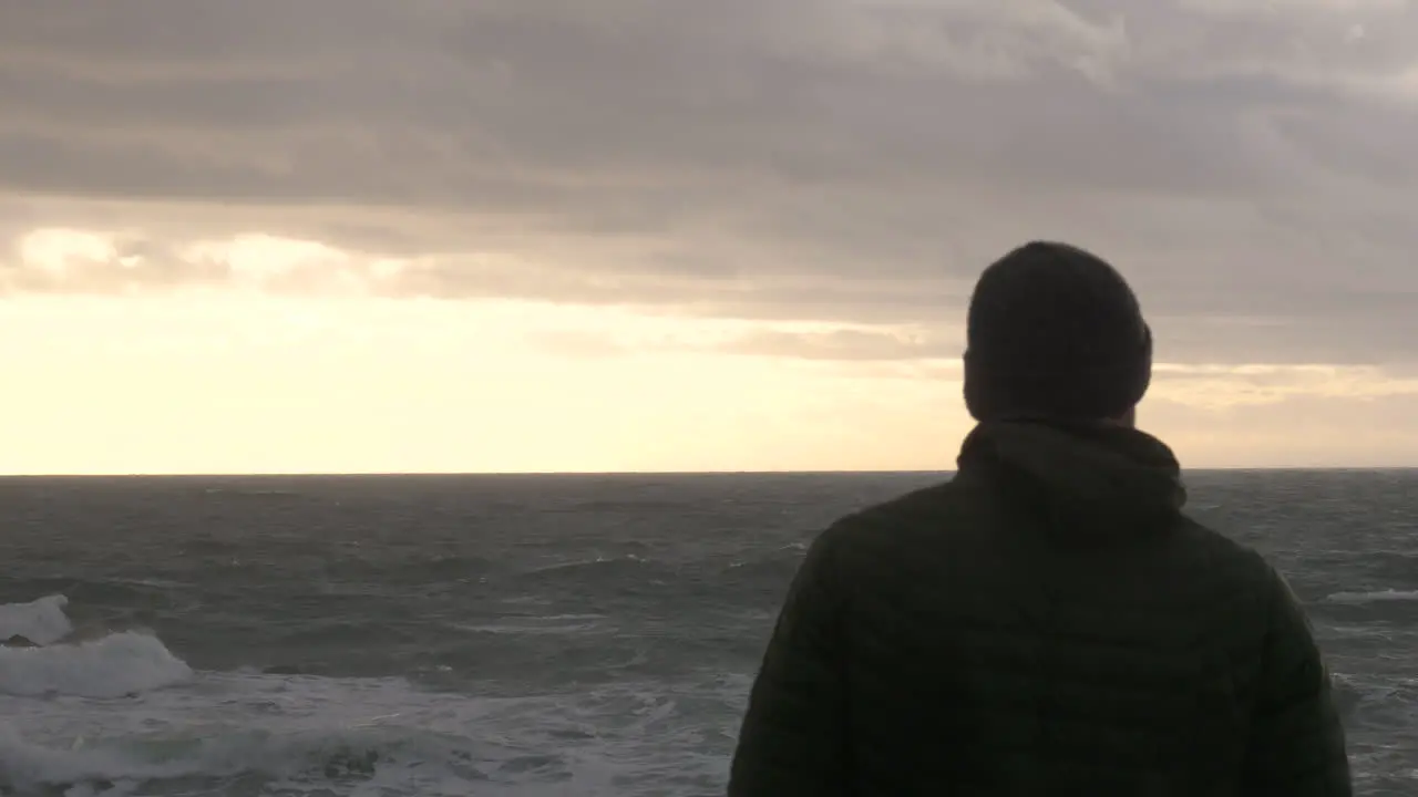 Silhouette Of A Sad Man Overlooking Rough Sea At Sunset