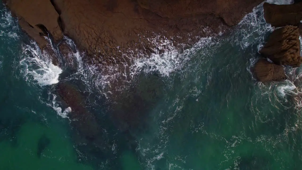 Aerial top view of constrast waves forming and abrupt rocks of the cantabrian coast in Isla a village of Cantabria Spain