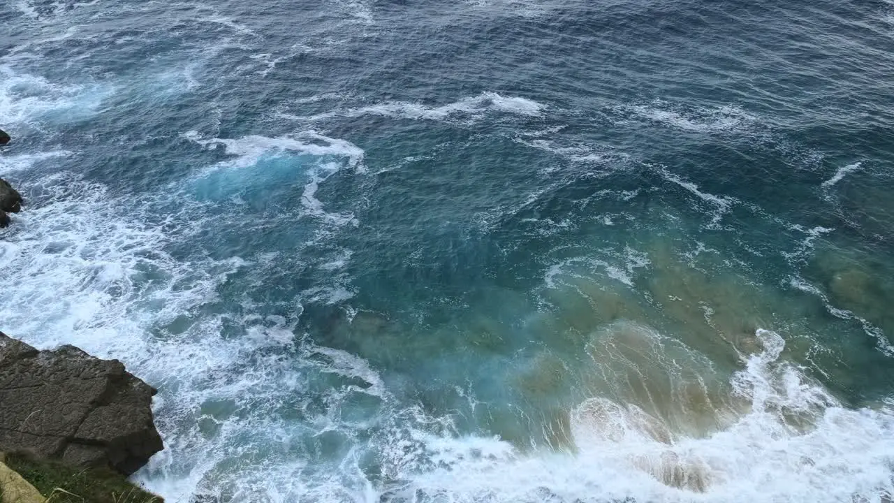 The waves of blue Cantabrian sea hitting the beach of the Isla island