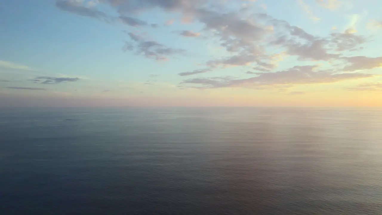 High altitude drone pan over tranquil ocean waters during a majestic sunset