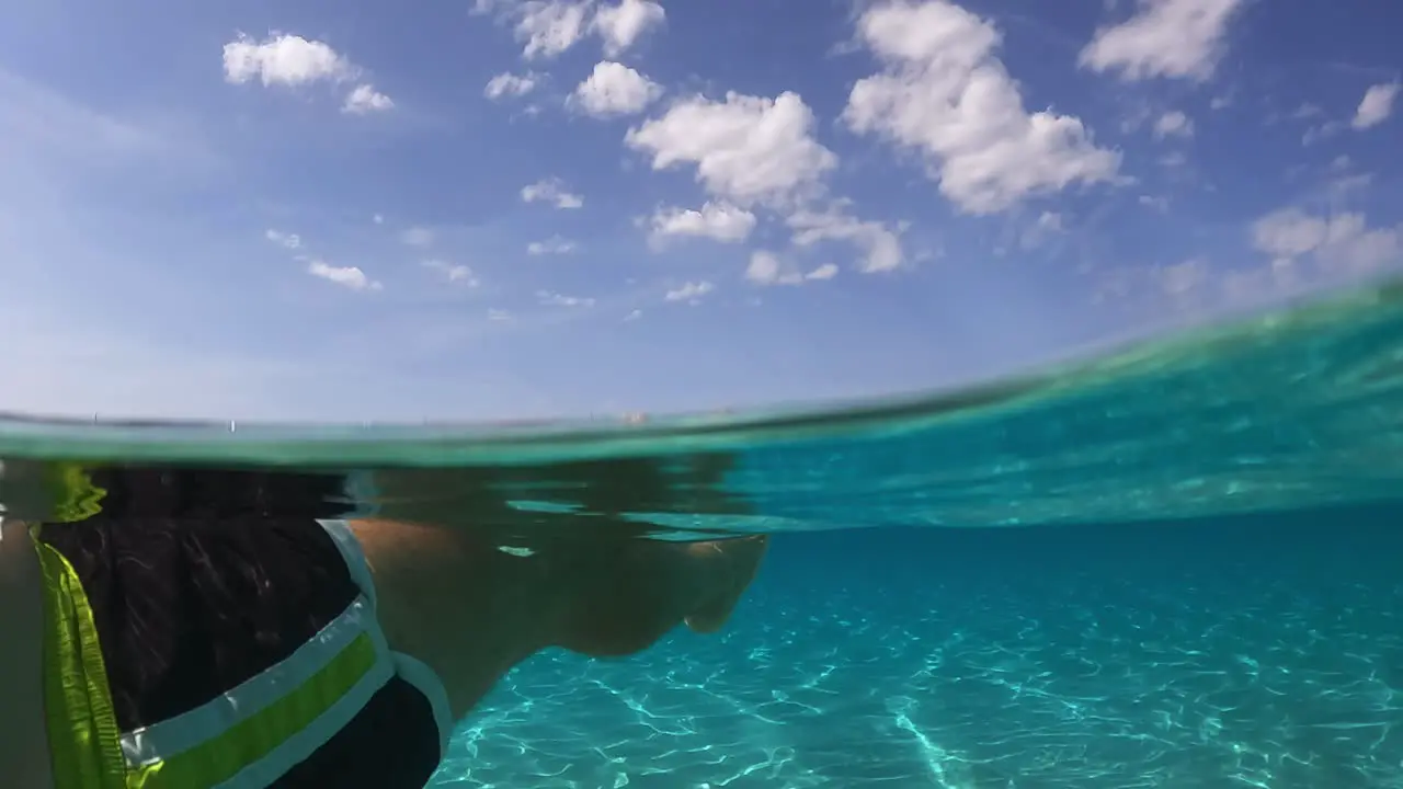 Personal perspective of man legs and feet floating on beautiful clear and transparent sea water of turquoise lagoon on tropical island