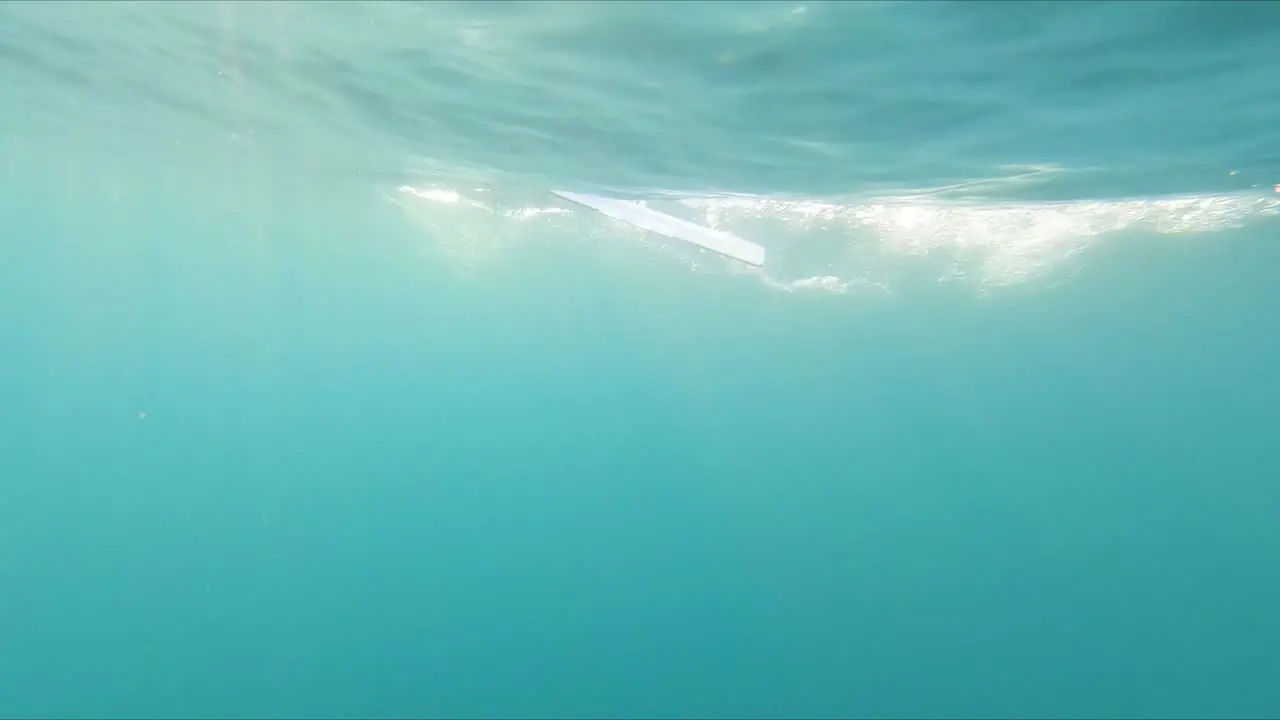 Underwater point of view swimming fast under sweeping rowing boat paddles