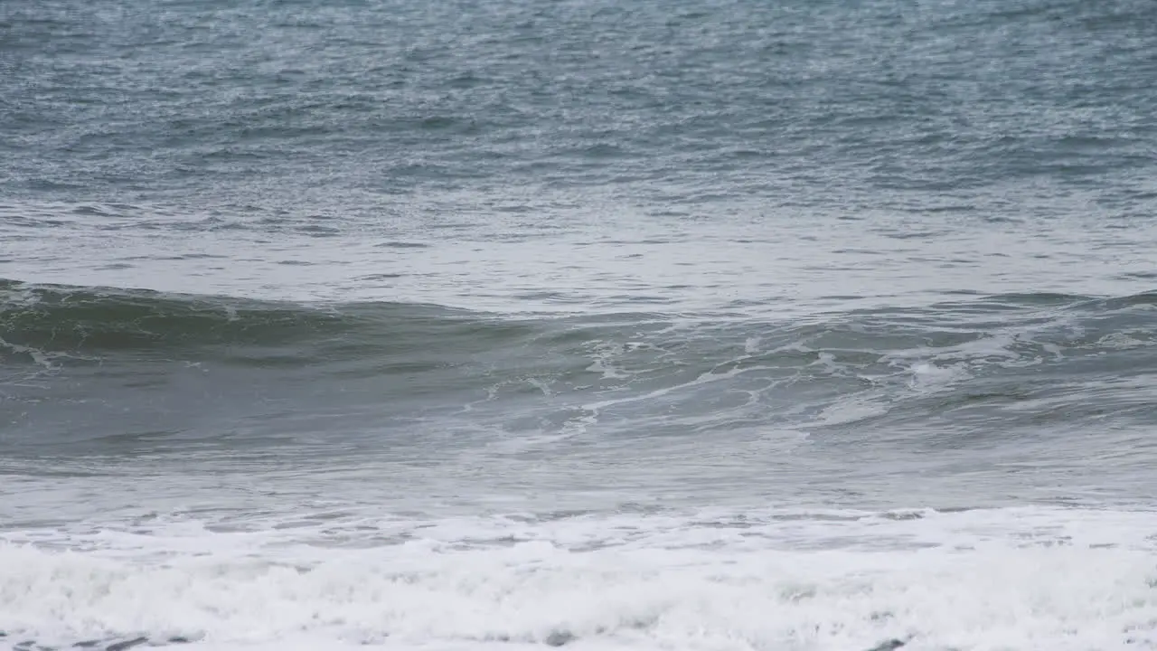 Swell wave forming in slow motion in the shore with a deep dark blue ocean behind it and white water spilling in high speed camera 120fps 4K footage